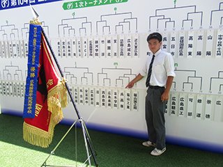 組み合わせが決まったボードの前で 優勝旗と一緒に記念写真です