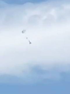 白い雲を背景に落下傘が開いて ロケットが降りています